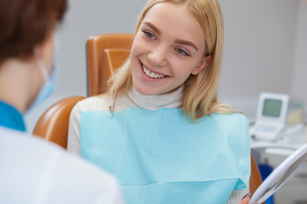 Smiling Woman at Dentist Appointment – Teeth Whitening in Irvine Young woman smiling during a dental consultation, discussing her bright new smile after teeth whitening – Teeth Whitening in Irvine